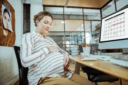 孕妇下班后坐在办公室, 摸她的肚子