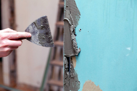 s hand smears cement glue on the wall with trowel to glue cerami