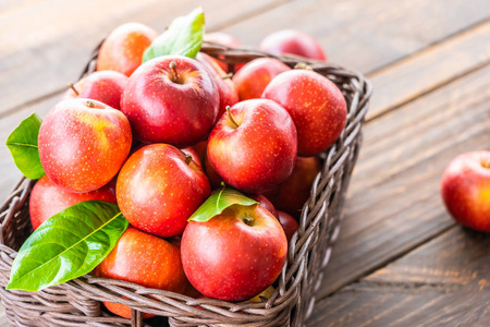 桌子上棕色篮子里有很多红苹果水果照片