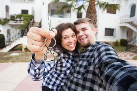 新家房地产和移动概念有趣的年轻夫妇展示新房钥匙