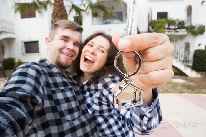 房地产, 房地产和租金概念快乐有趣的年轻夫妇显示他们的新房子的钥匙