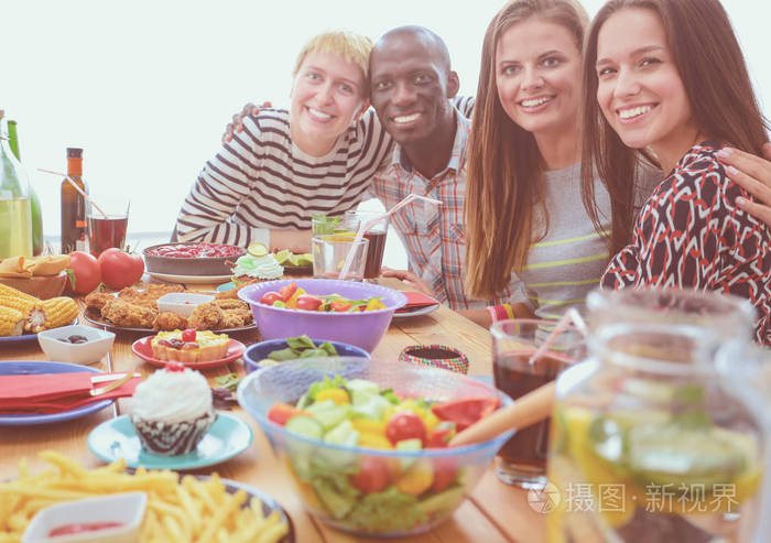 顶视图的一群人在一起时坐在木桌吃饭.在桌子上的食物.人们吃快餐