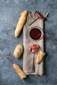 反胃肉切片果酱在叉子上与工匠面包品种和一杯红酒在布上蓝色纹理背景。 平坦的铺设空间。 开胃菜概念