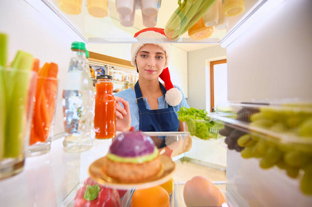 女性站附近打开冰箱充分的健康食品，蔬菜和水果的画像。女性肖像