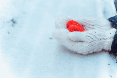 女手在针织白色手套与心雪在冬季。 爱和圣瓦伦丁舒适概念共空间