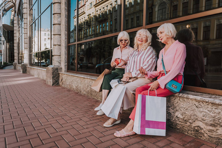三名时尚的女性养老金领取者坐在商场附近