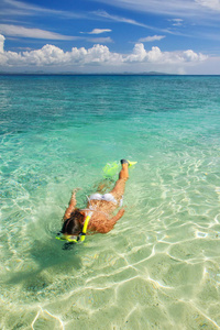 年轻女子在热带岛屿附近清澈的浅水中浮潜