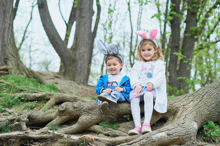 可爱有趣的女孩和男孩带着复活节彩蛋在公园。 复活节的概念。 孩子们在复活节玩复活节彩蛋。 家庭假日
