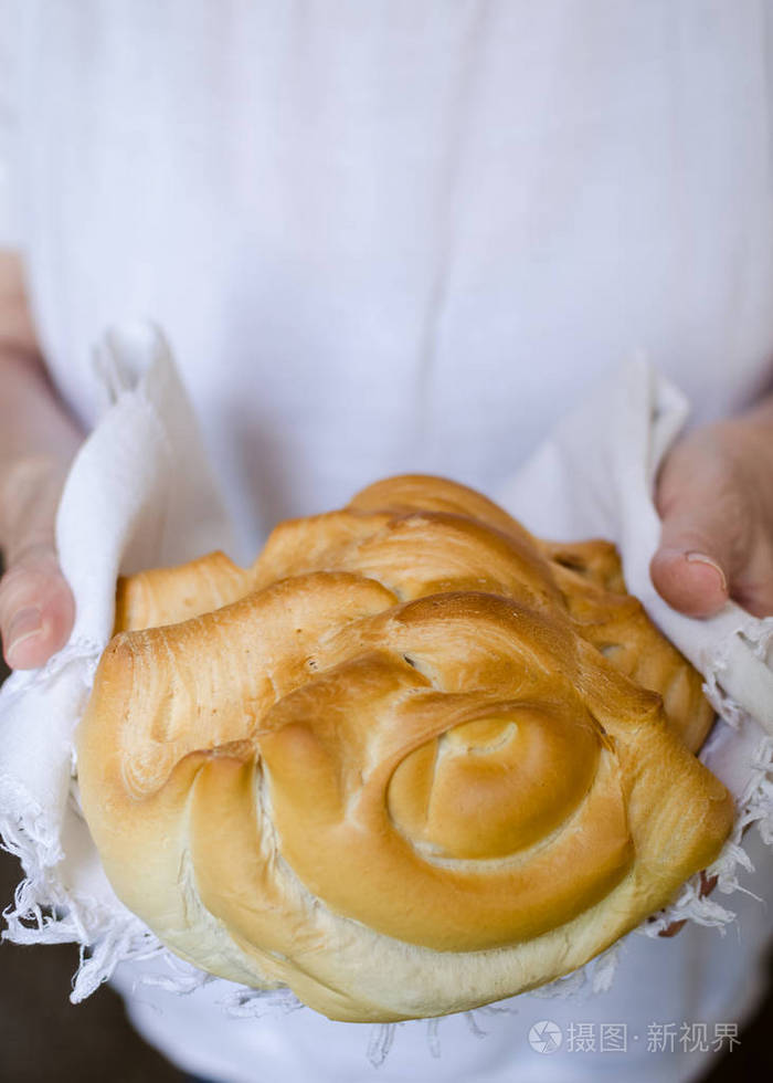 女人手里的圆面包. 面包师拿着一个漂亮的新鲜烘焙的温暖面包. 乡村复