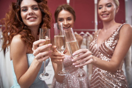 年轻快乐的女士们对着香槟酒眼镜叮当作响