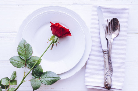 s Day romantic tabble setting with red rose, plates, cutlery on 