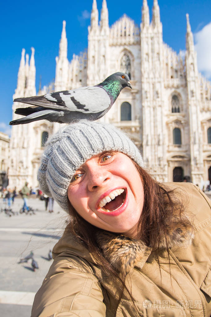 冬季旅行度假和鸟类的概念年轻有趣的女人采取自拍与鸽子附近米兰大