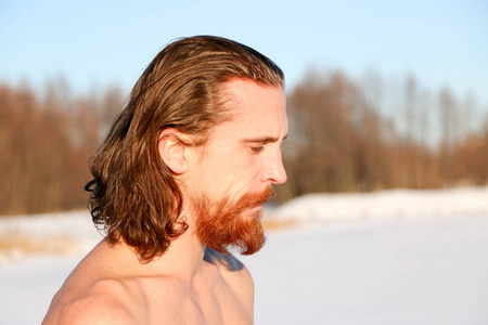 年轻，苗条，英俊，有着红色胡须和长发的运动型男人，着，穿着黑色短裤，在一个工业景观的背景下，在冬天潜入冰冷的水中，乌克兰，肖