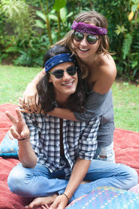 年轻迷人的微笑的男人和女人长头发和太阳镜坐在地毯上的枕头.