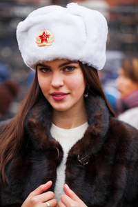 俄罗斯美女。莫斯科一个年轻漂亮的女孩戴着一顶带毛皮帽子的白帽子对着一个红色广场的画像