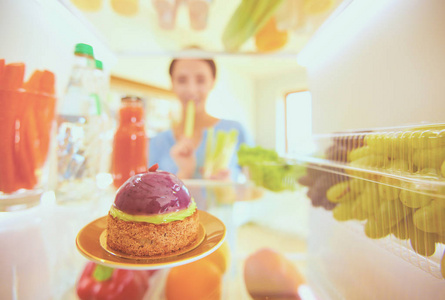 女性站附近打开冰箱充分的健康食品，蔬菜和水果的画像。女性肖像