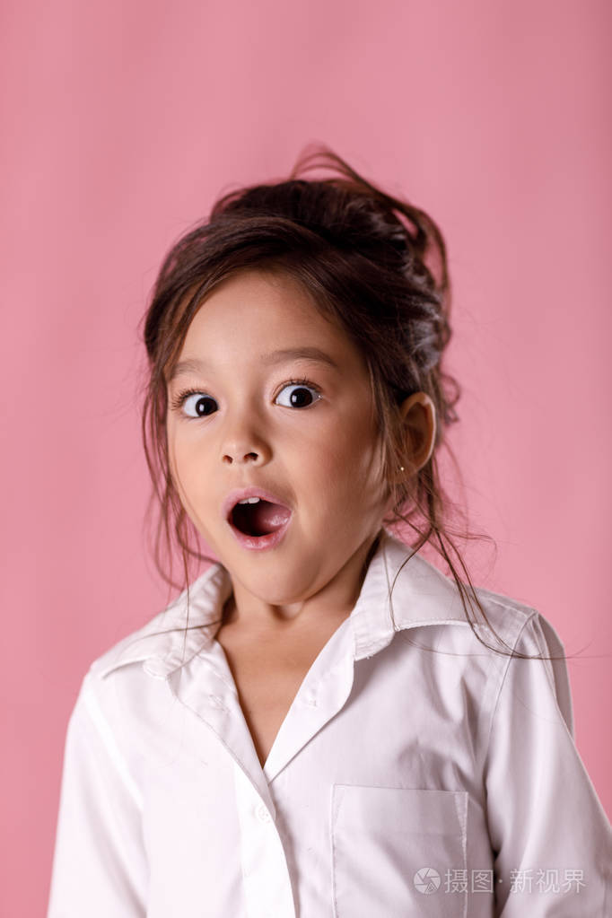 可爱的惊讶小女孩在白衬衫与发型
