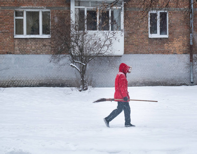 穿着红色外套和长扫帚的人。 大雪天气的户外冬季形象