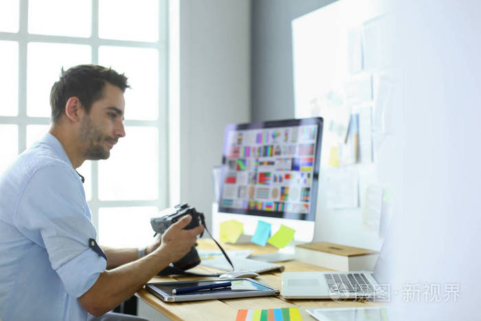 年轻设计师坐在笔记本电脑和电脑前的平面画室,在网上工作