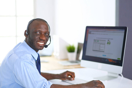 非裔美国商人戴着耳机在他的笔记本电脑上工作。