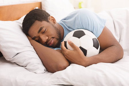 非洲裔美国人睡觉和拥抱足球