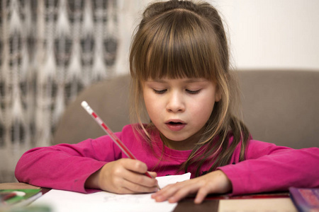 可爱的，漂亮的，严肃的，小女孩的肖像，用铅笔在模糊的背景上画在纸上。 艺术教育创造力做作业和儿童活动理念。