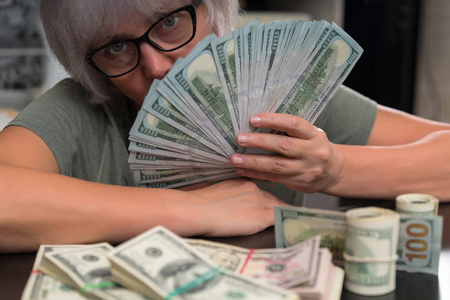 一个女人手里拿着一大堆100美元的，脸上藏着一大叠卷和捆包，以一种概念性的金融形象出现在她面前