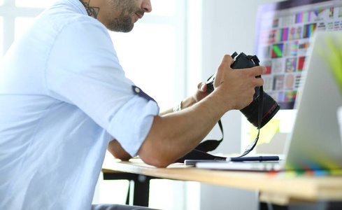 年轻设计师的肖像坐在平面工作室前的笔记本电脑和电脑, 而在线工作