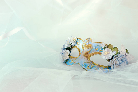 照片优雅和精致的蓝色威尼斯面具与花装饰薄荷雪纺背景。