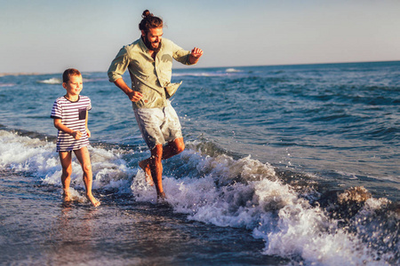  boy child, running and having fun in the sand and waves of a su