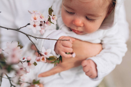 快乐快乐的孩子的画像在白色衣裳在树花开花背景。一家人在外面玩耍。妈妈乐呵呵地抱着小女儿