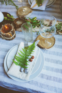 乡村节日餐桌细节与野生蕨类植物手工装饰和蜡烛。 夏天晚上的乡村家庭晚餐。