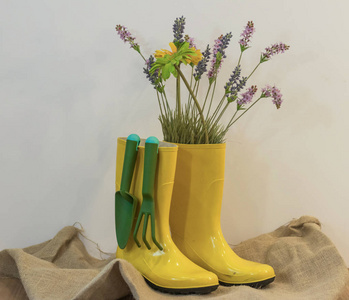 雨靴与园艺设备和春天花的生态背景从麻布