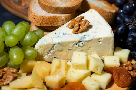 奶酪拼盘放在木板上，面包和水果俯视图