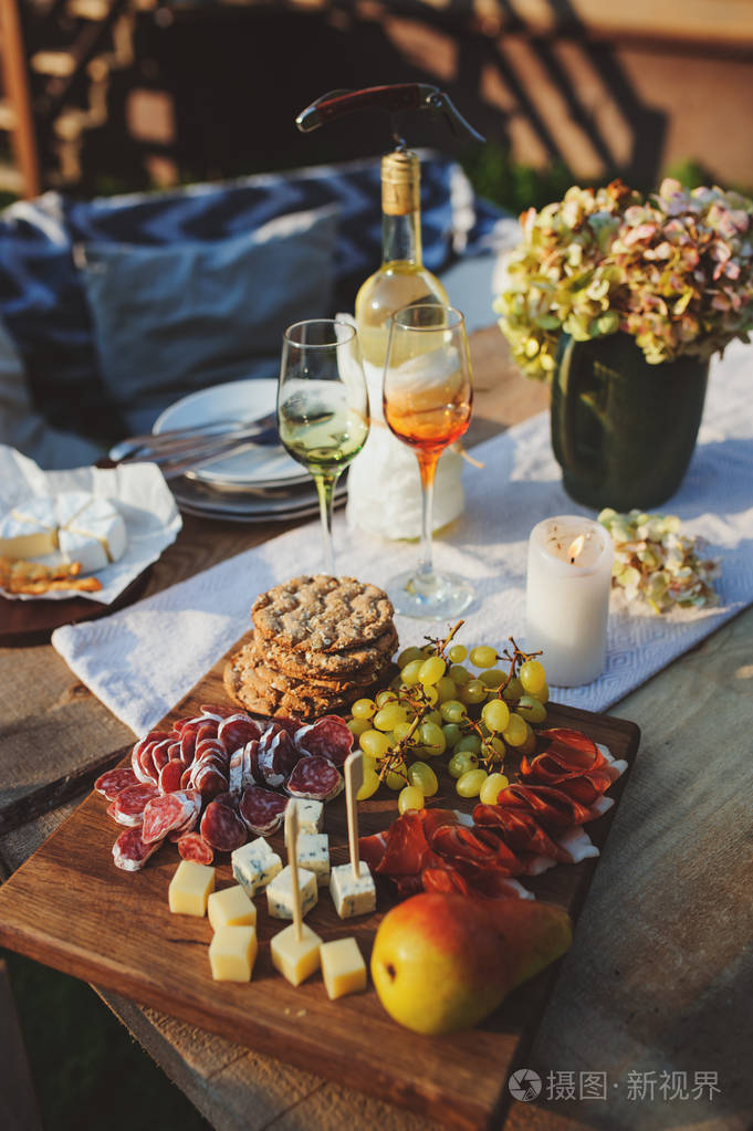 美味的奶酪火腿和水果,在夏季花园聚会上提供木制砧板