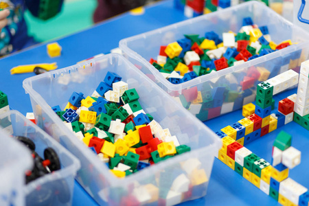 s hands playing with colorful plastic bricks at the table. The f