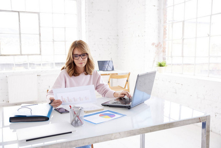 财务顾问,专业妇女坐在办公桌上用笔记本电脑工作的肖像.照片