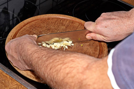 厨师用刀在切割板上切大蒜蒜茸。
