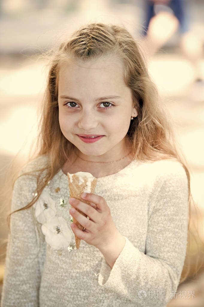 小女孩喜欢吃冰淇淋.孩子微笑与长的金发.食物,小吃和甜点.暑假和放松
