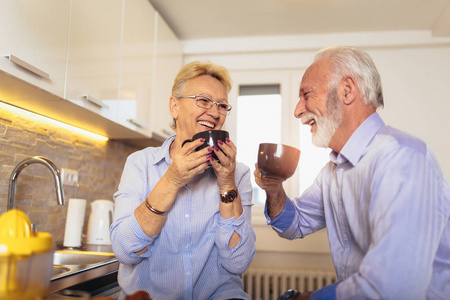 快乐的老年男女夫妇坐在一起，微笑着喝茶或咖啡