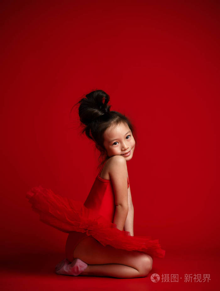 可爱的小女孩芭蕾舞演员芭蕾舞演员在美丽的礼服是在红色跳舞