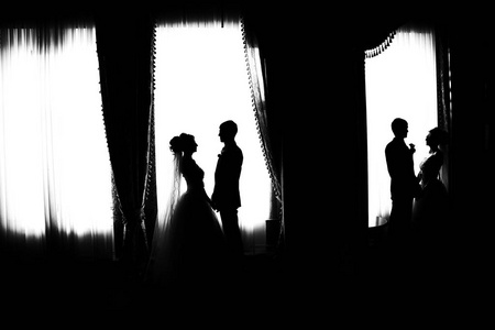 新郎新娘的剪影。黑白照片。新娘和新郎倒映在镜子里。新娘和新郎在大窗户。