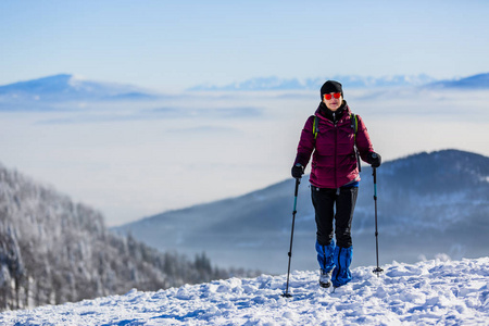 在阳光明媚的一天，带背包徒步旅行的女性旅行者在贝斯基迪山徒步旅行，冒险概念积极度假，户外活动在森林中的雪，波兰形象