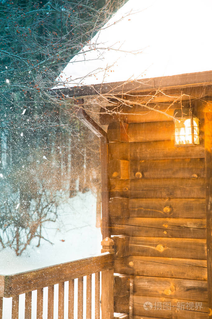 冬天的傍晚,木屋里降着雪,门廊里的灯光闪闪发光