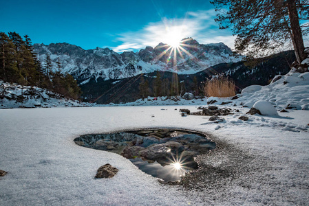 在德国巴伐利亚，美丽的艾布西湖艾布西湖有冰雪，祖格斯皮茨山在后面有云和太阳