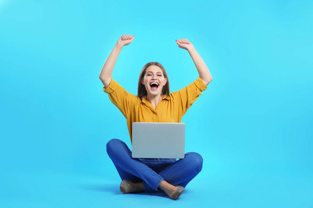 情绪激动的年轻女子，带着笔记本电脑庆祝彩色背景的胜利