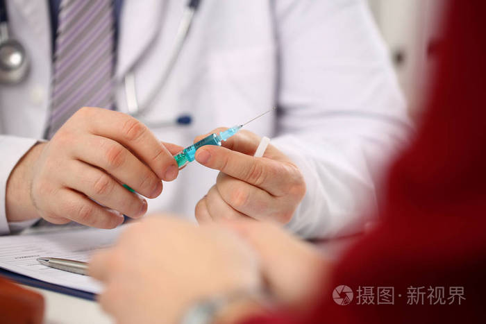 医生注射器手臂在无菌均匀的固定注射器