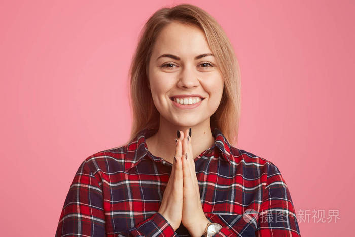 幸福的年轻女人的肖像带着愉快的微笑乞求一些快乐的表情穿着格子衬衫