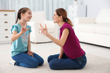 听力受损的母亲和她的孩子在室内用手语说话照片