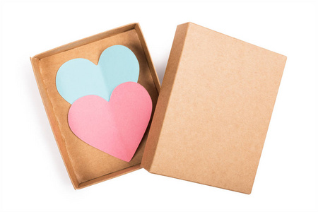 两个纸的心在纸板箱与盖子查出在白色背景。粉红和蓝色的心从纸上剪下来